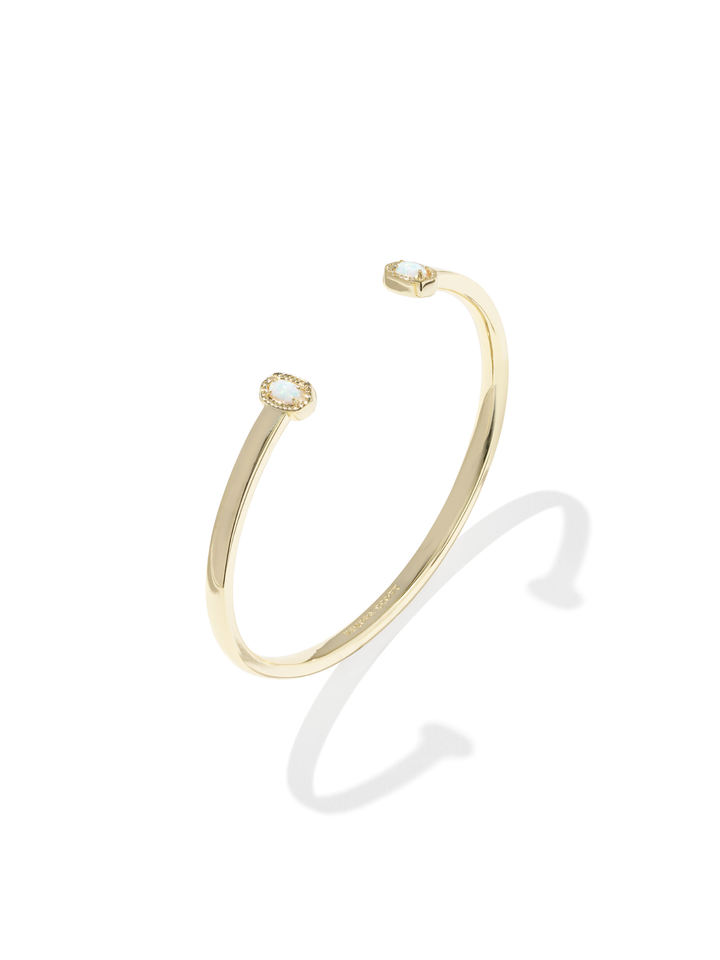 A slim gold cuff bangle bracelet with two small round clear gemstones, one at each end, displayed on a clean white background with a soft shadow.