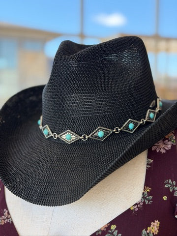 A black woven cowboy hat with a decorative silver band featuring turquoise-colored diamond-shaped accents, displayed on a mannequin head.