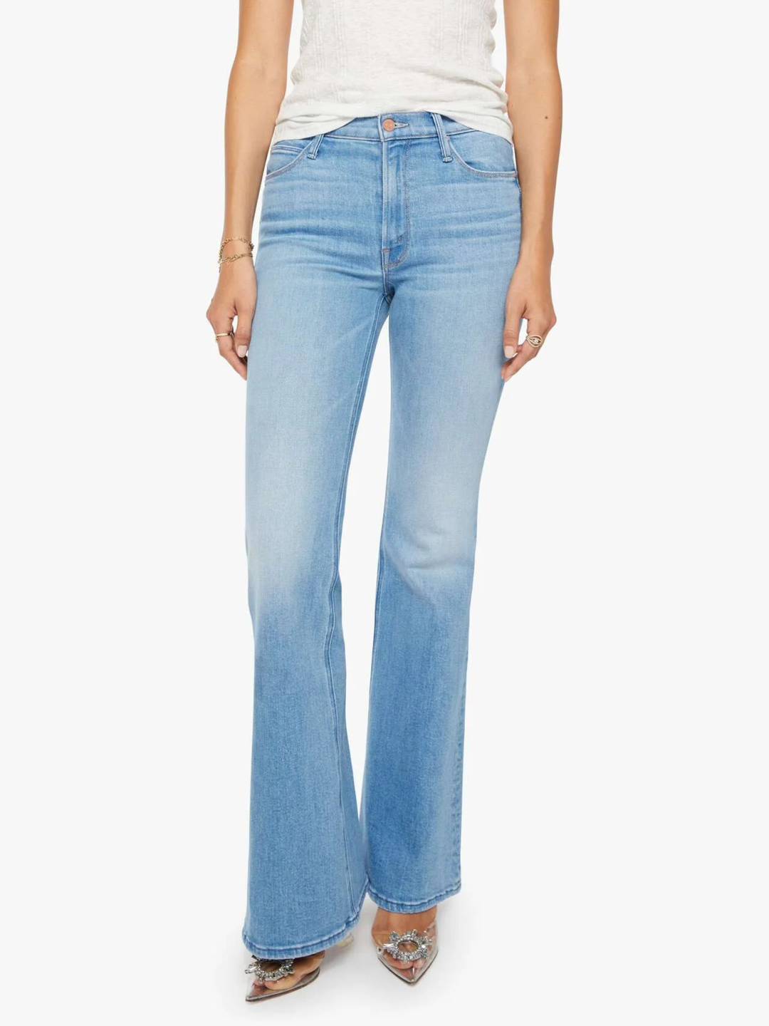A model wearing light-wash blue flare jeans, paired with a white top and pointed shoes, shown against a plain white background.