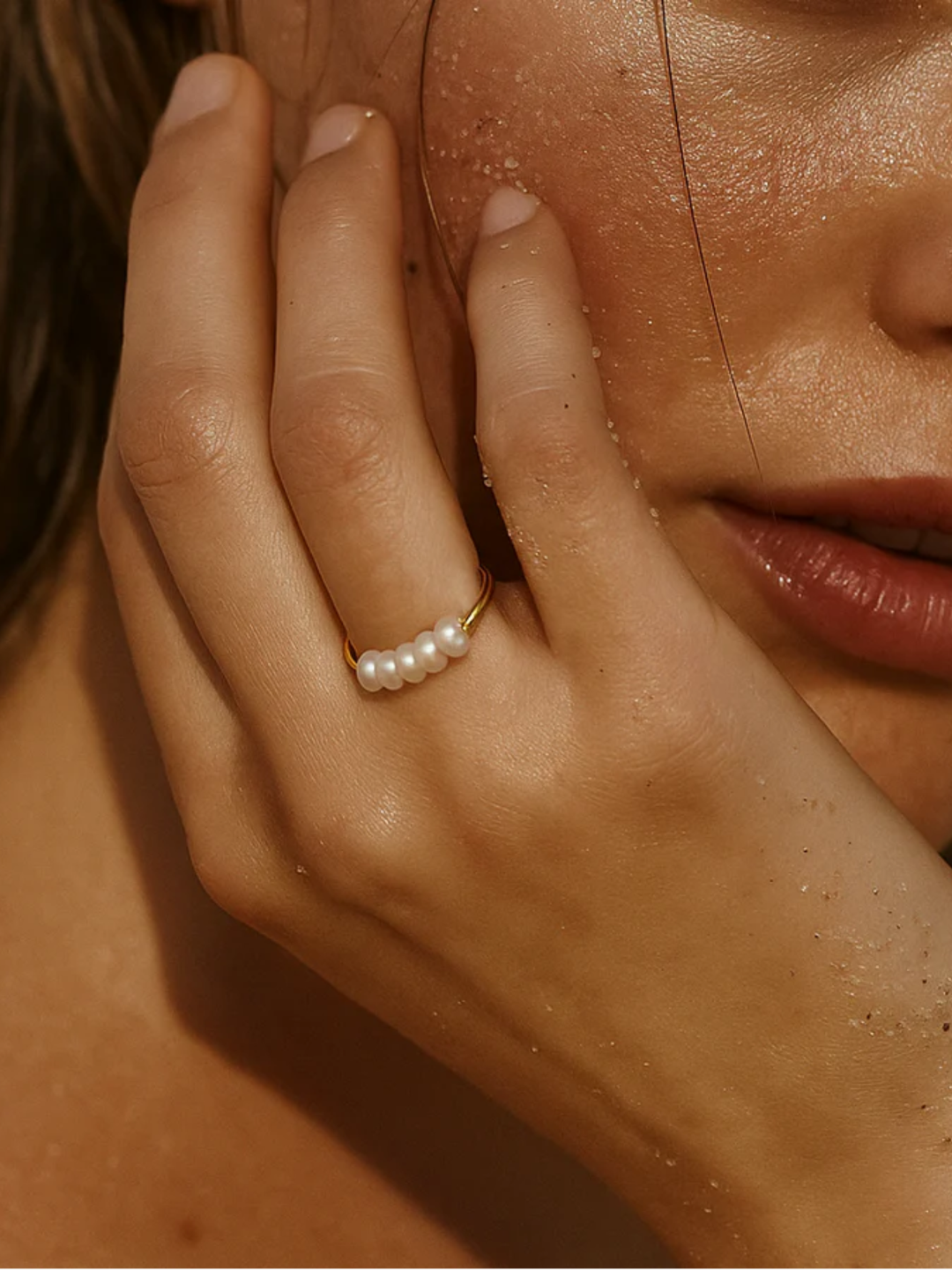 Close-up of a hand wearing a pearl ring with a blurred background