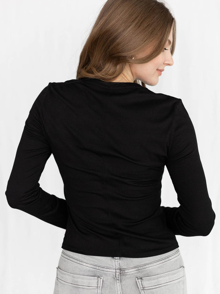 Woman wearing a black long-sleeve top with a white background
