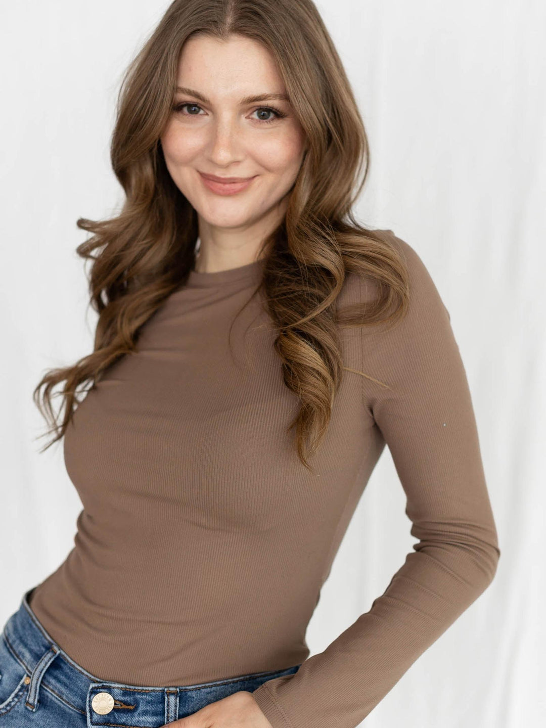 Woman wearing a brown long-sleeve top against a white background