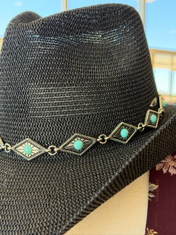 A black woven fedora-style hat with a silver-toned band featuring repeating diamond motifs and turquoise-colored stones, photographed close up.