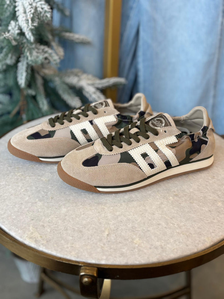 Pair of camouflage sneakers on a round table with a blurred background