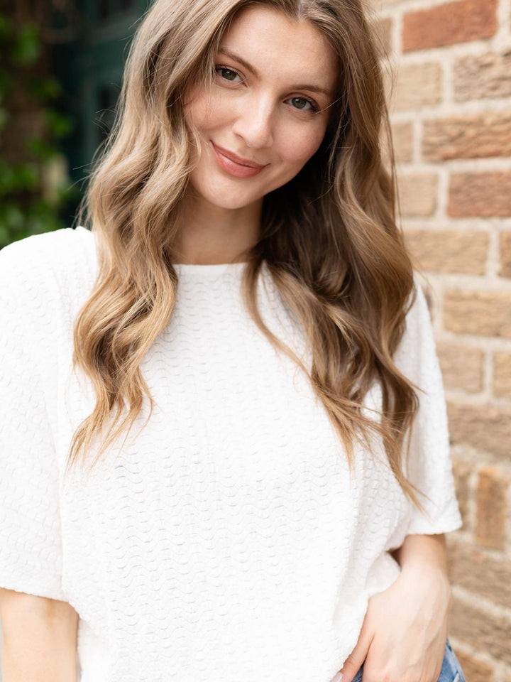 Woman wearing a white Allie Rose Wavy Texture Knit Dolman with a round neckline and dolman sleeves.