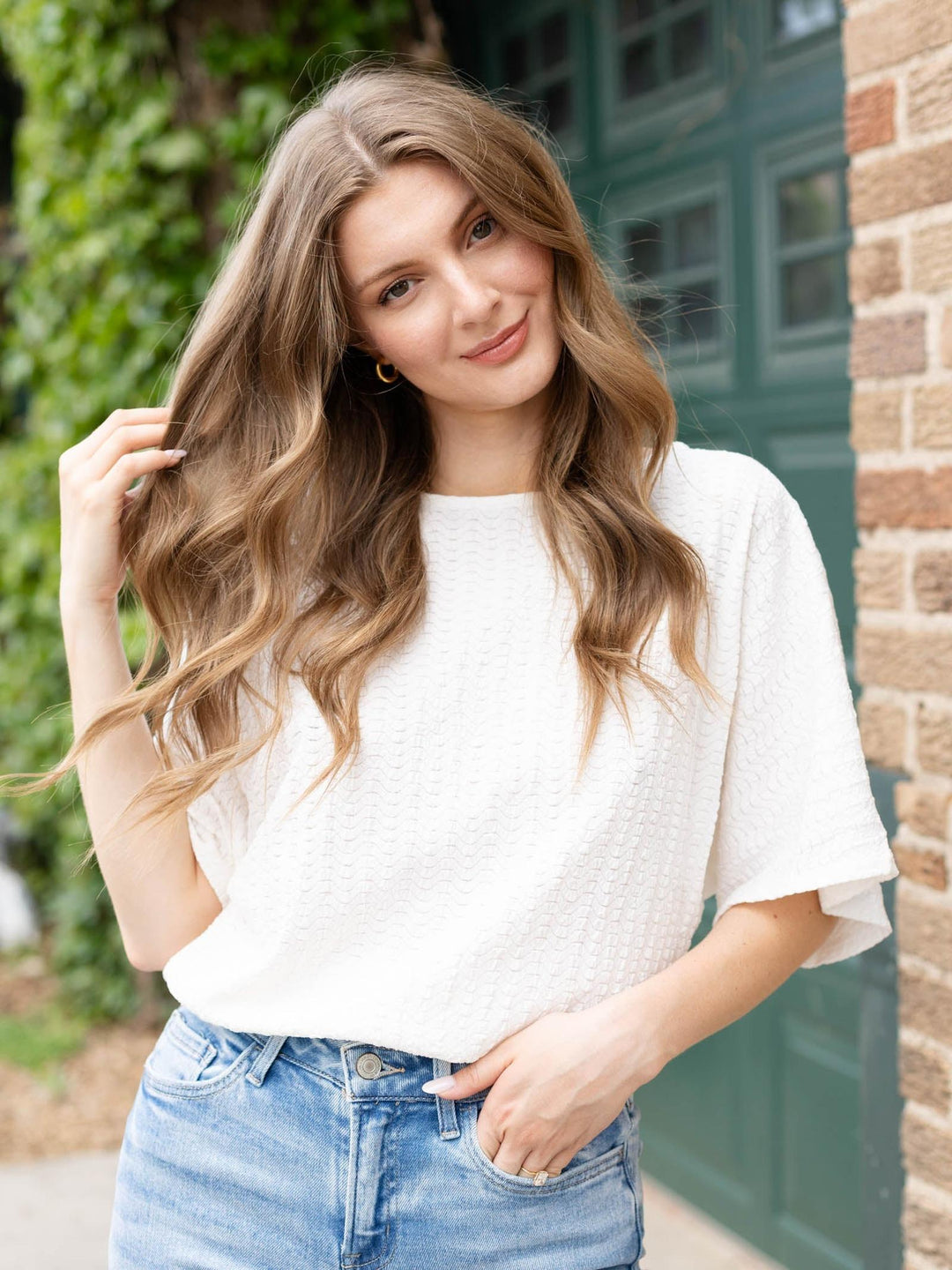 Model in Allie Rose Wavy Texture Knit Dolman top, light wash jeans, and gold hoop earrings.