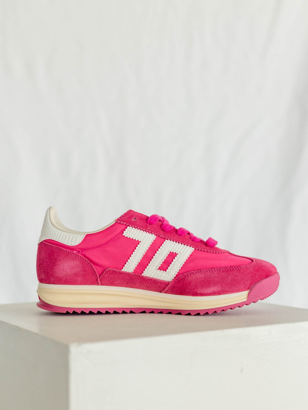 Pink sneakers with white accents on a light gray background