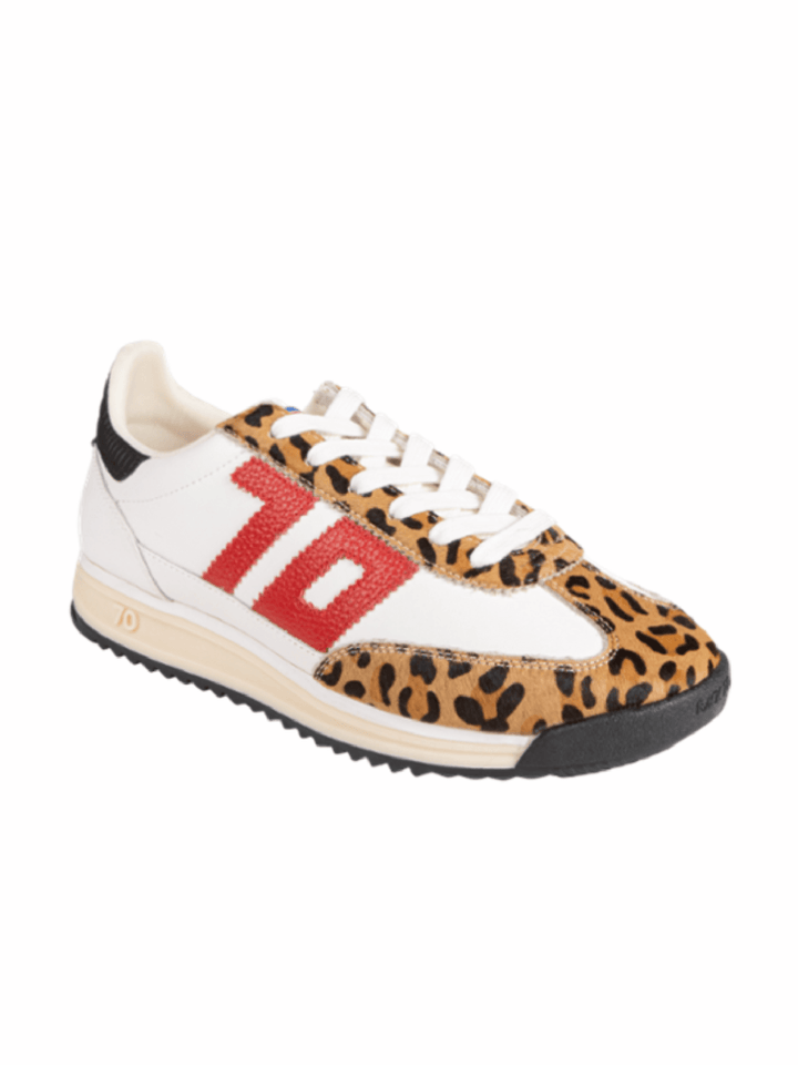 A low-top sneaker featuring a white leather upper, a tan and black leopard print pattern on the toe and side overlays, a large red &