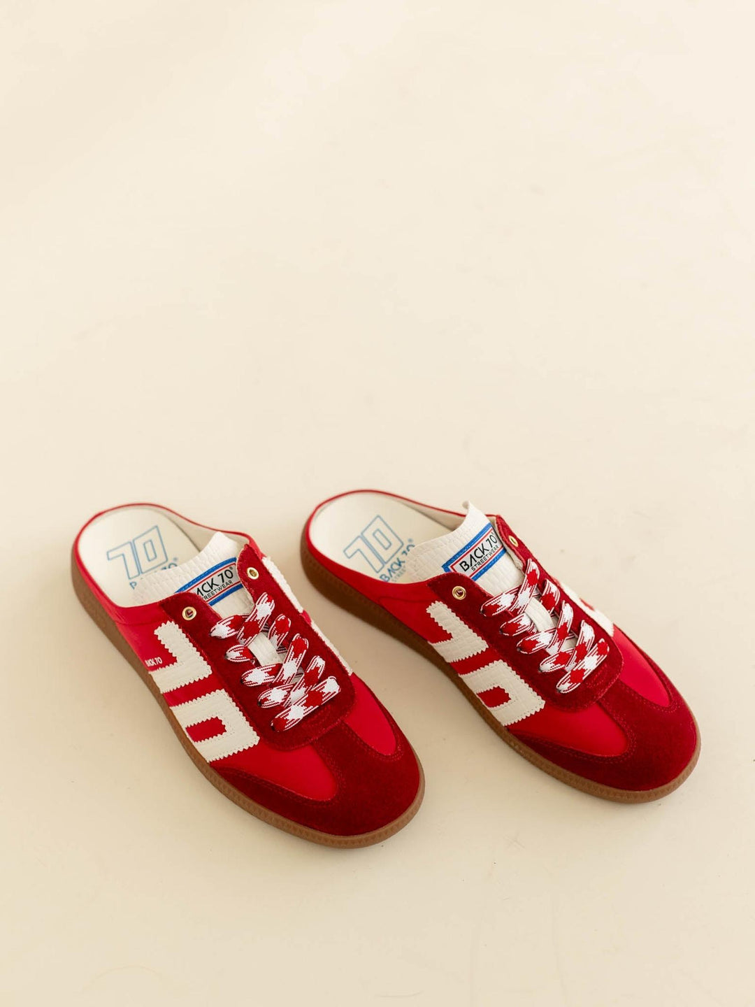 Red sneakers with white laces on a beige background