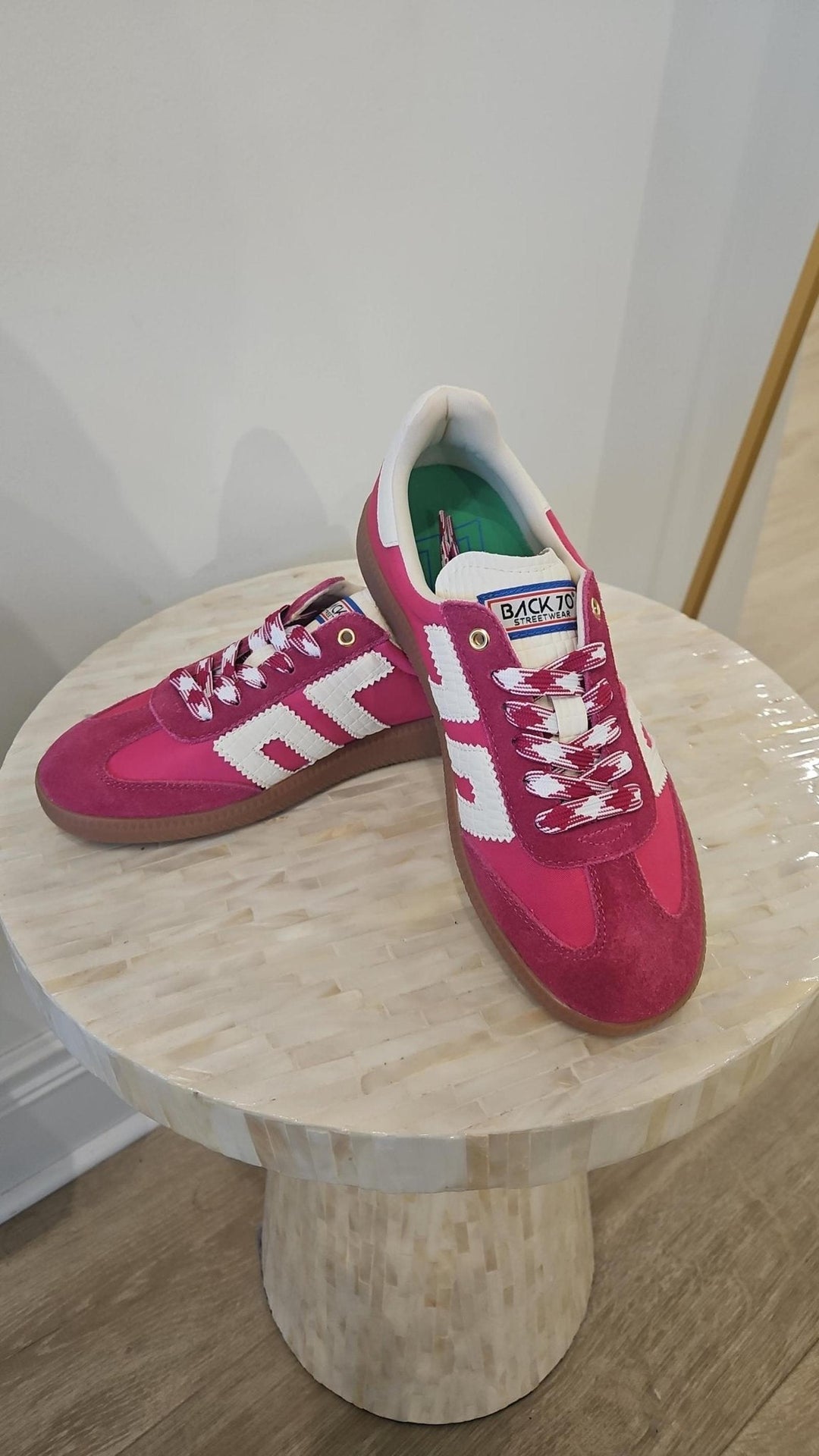 Red and white sneakers on a wooden stool against a white wall