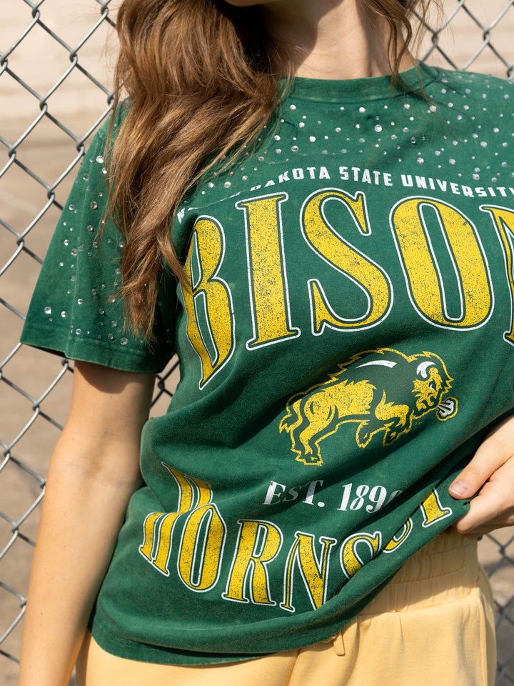 A close-up of a person wearing a green distressed graphic t-shirt with yellow and white &