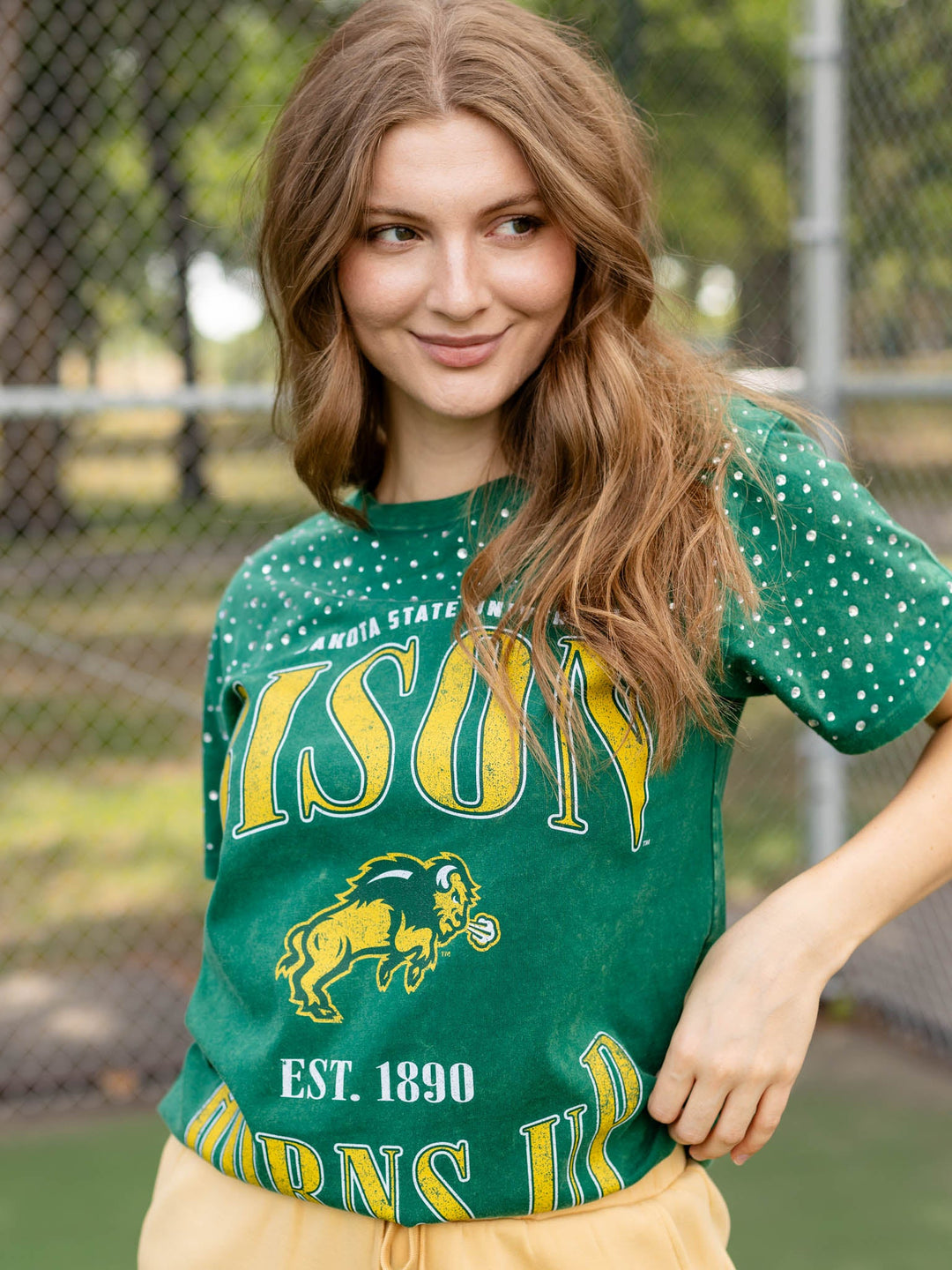 A woman wearing a green short-sleeve t-shirt with yellow and white &