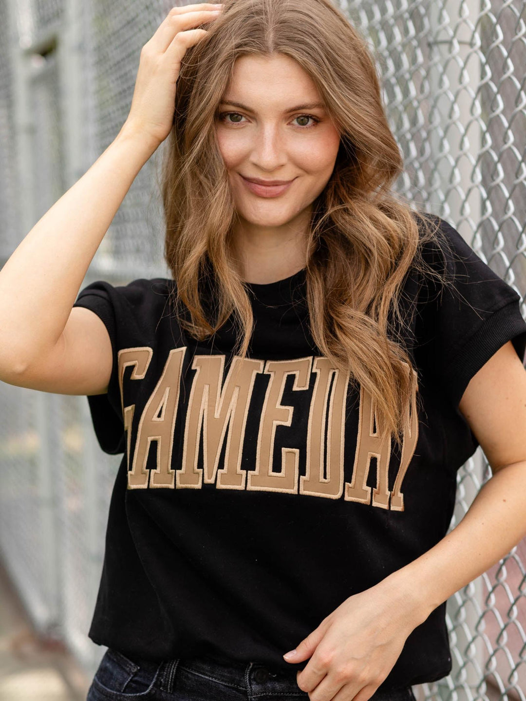 A woman with long wavy brown hair wearing a black t-shirt with &