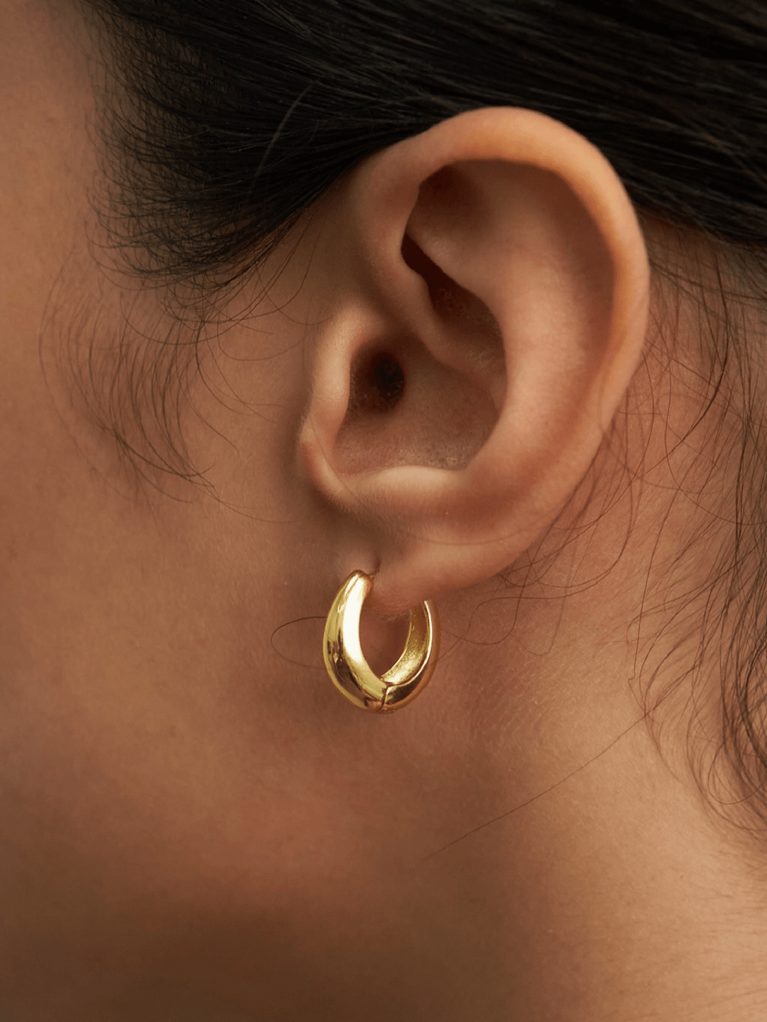 Gold hoop earring worn by a person