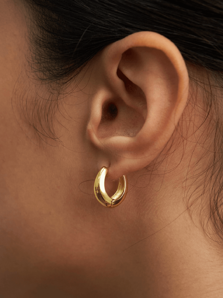 Gold hoop earring worn by a person