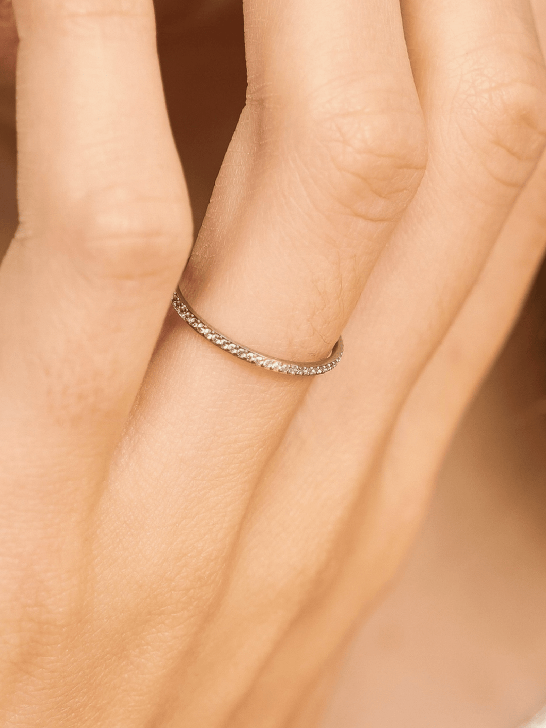 Close-up of a hand wearing a silver ring with a blurred background