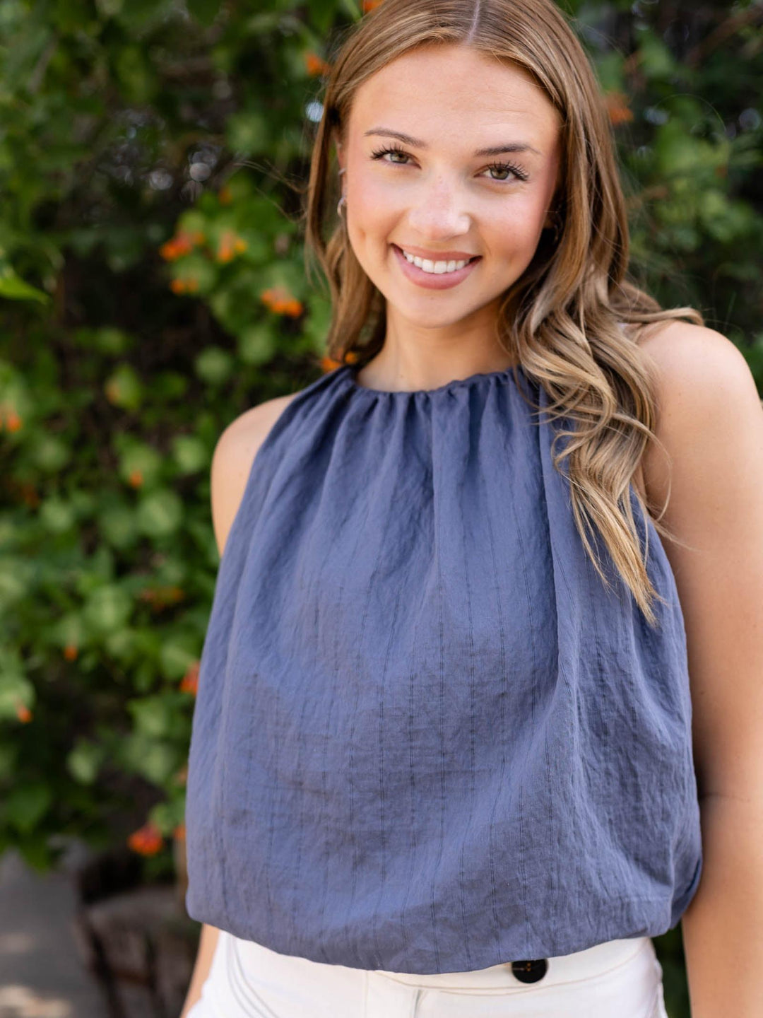 Model wears a Navy bubble striped tank top with a flowy silhouette and delicate thin stripes.