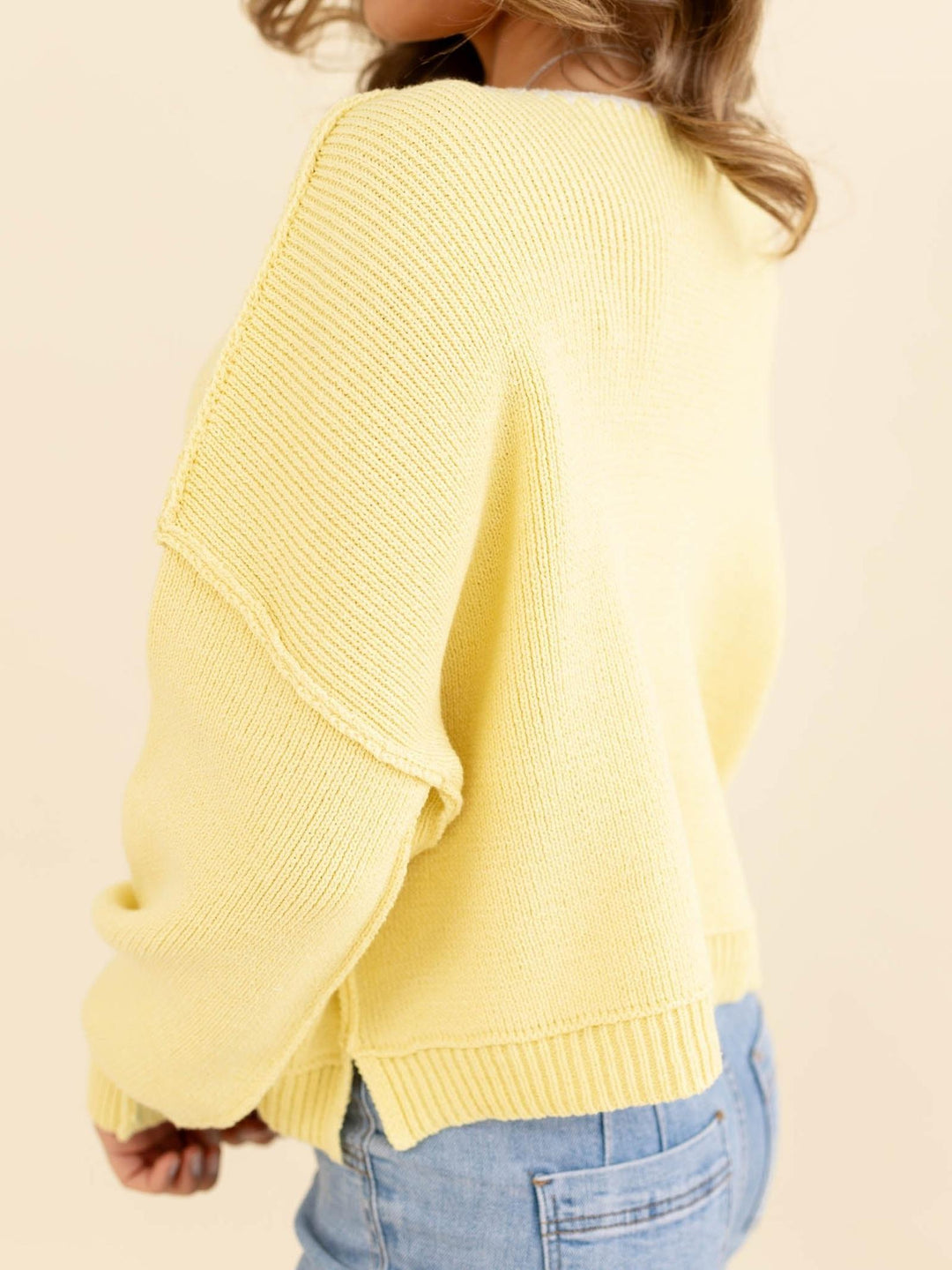 Yellow sweater worn by a person on a beige background