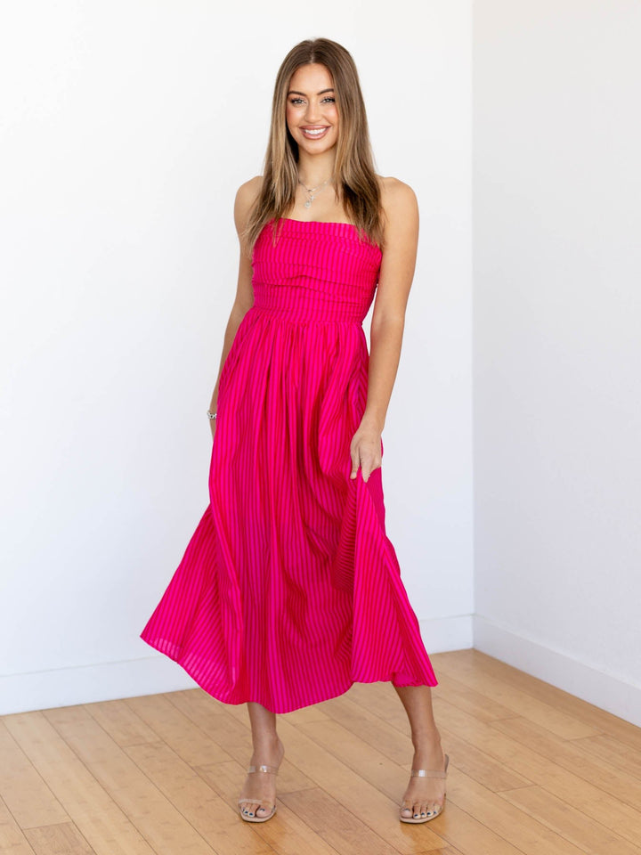 Woman wearing a bright pink dress in a minimal indoor setting