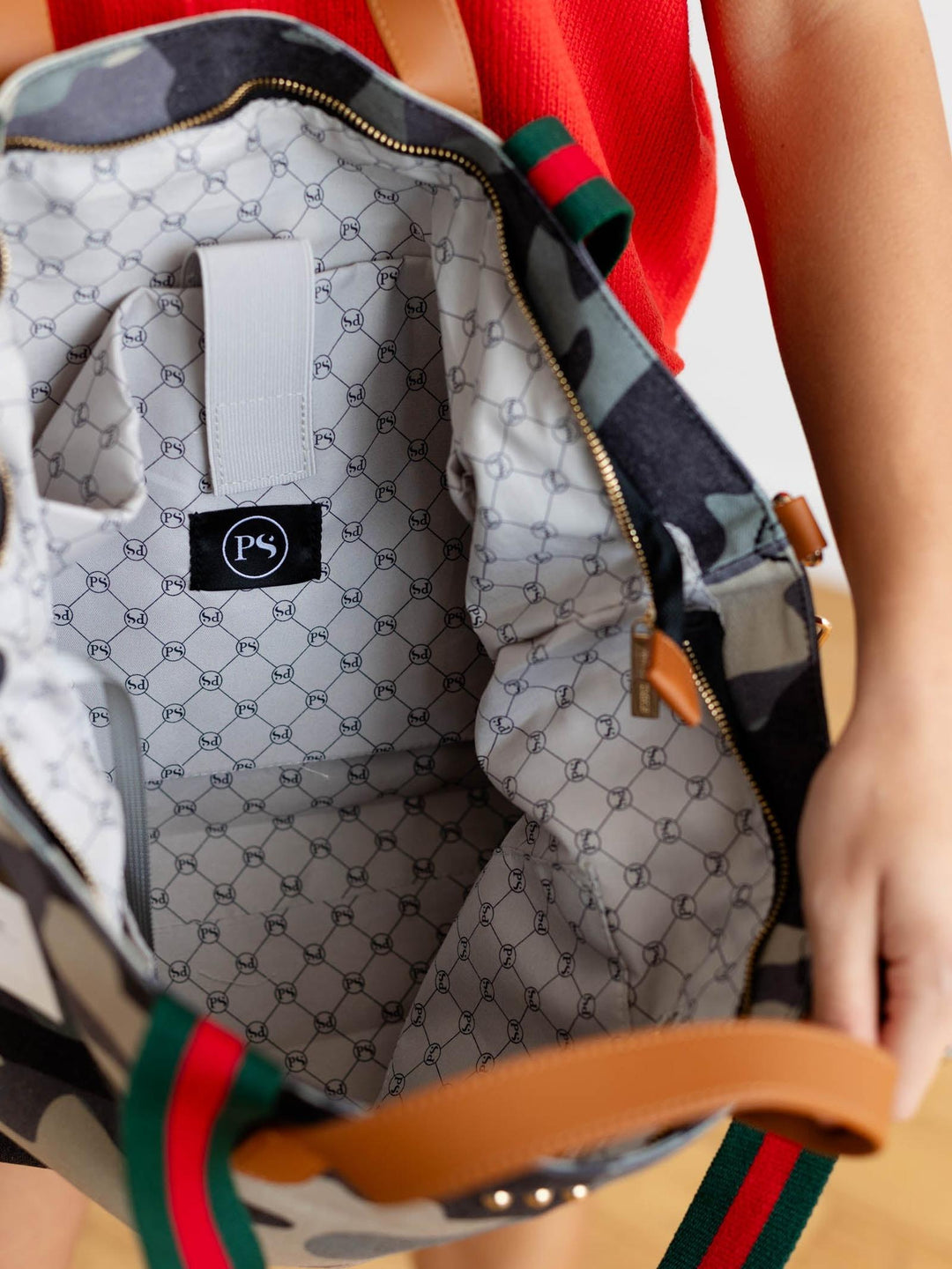 Close-up of a patterned bag with a visible brand logo, held by a person.
