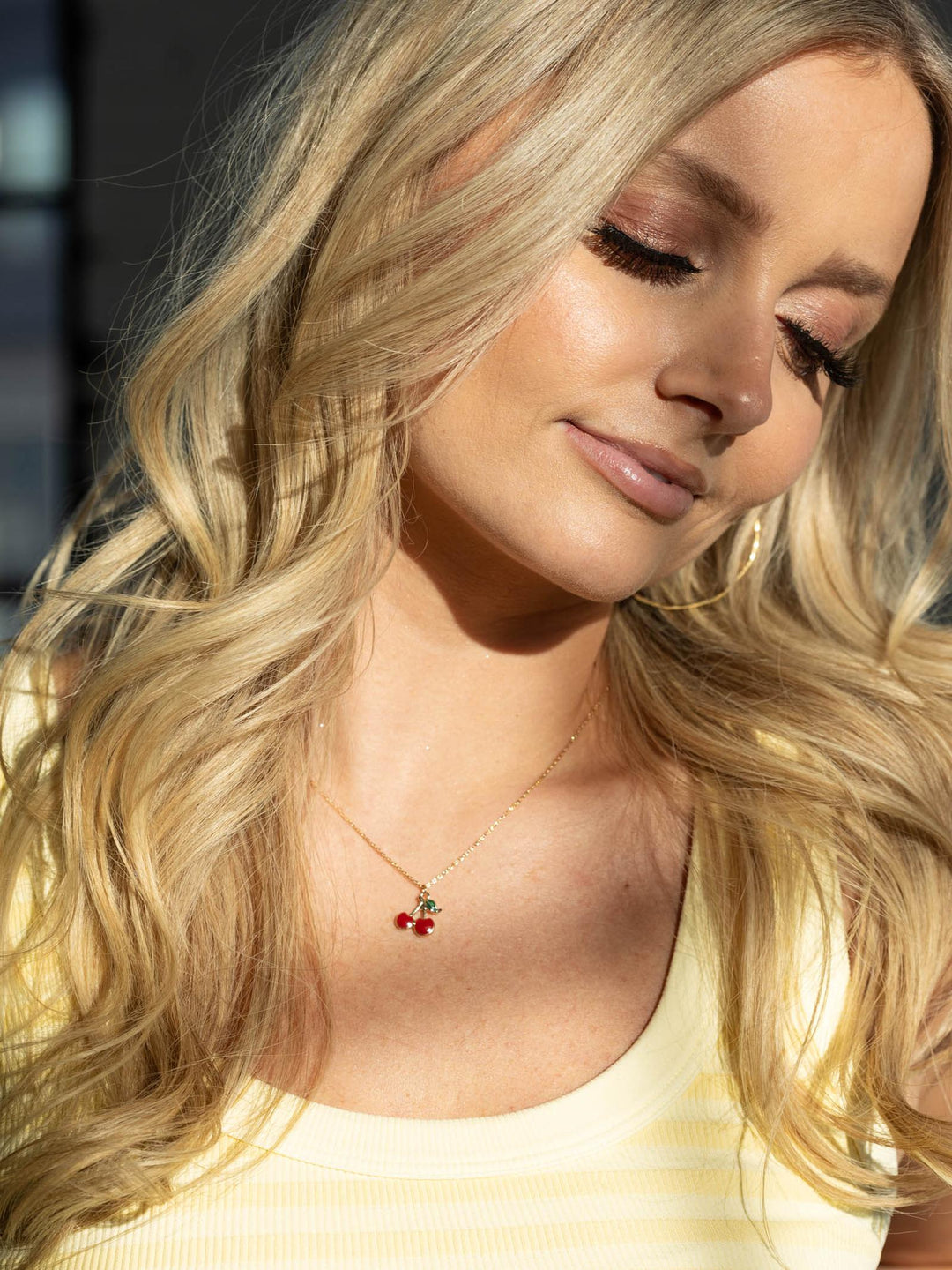 Woman with blonde hair wearing a necklace with red berries.