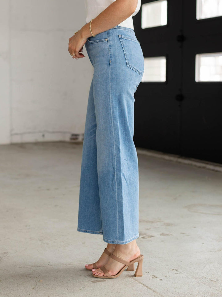 Person wearing light blue jeans in a minimal indoor setting
