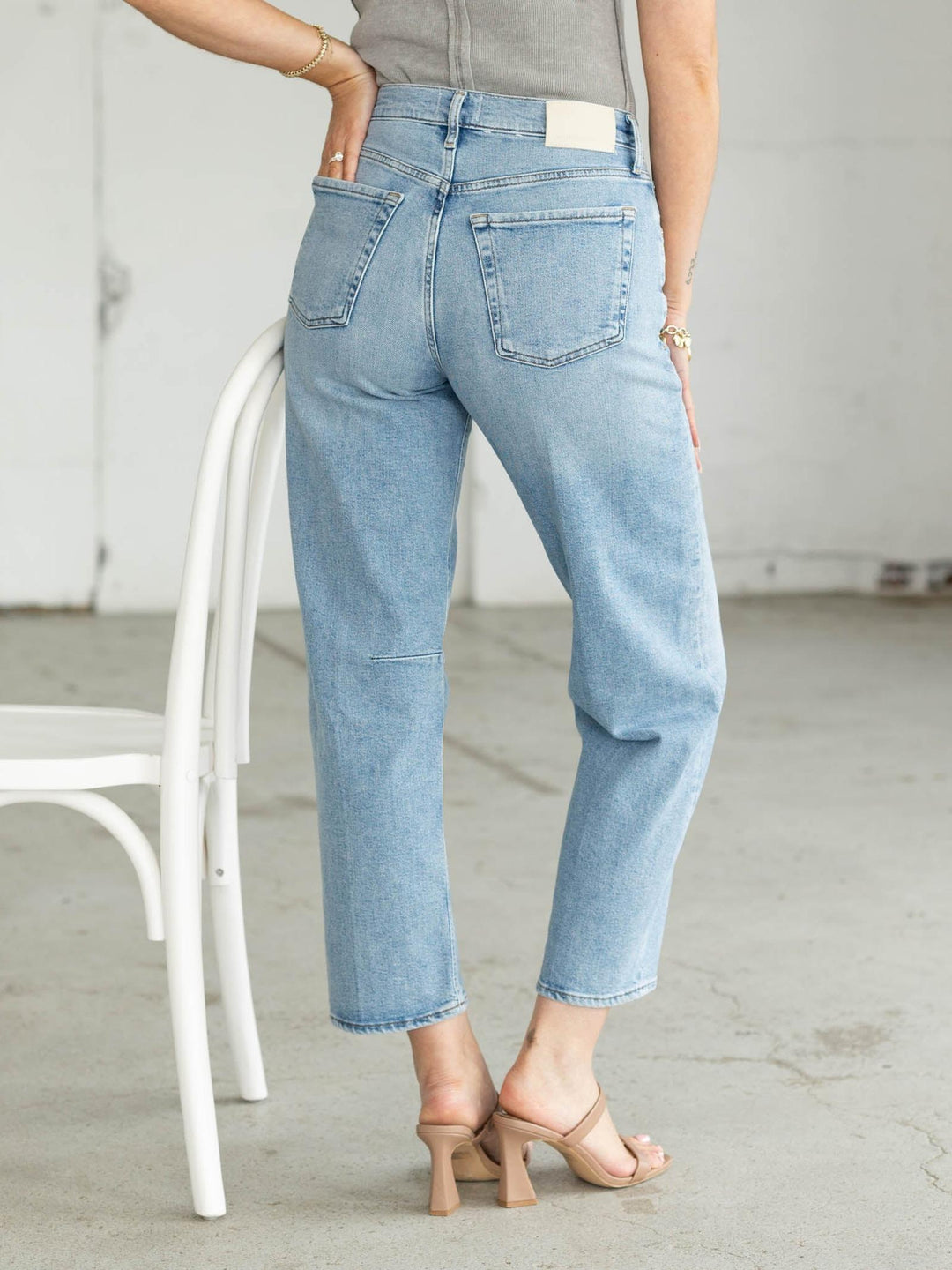 Light blue jeans worn by a person sitting on a white chair.