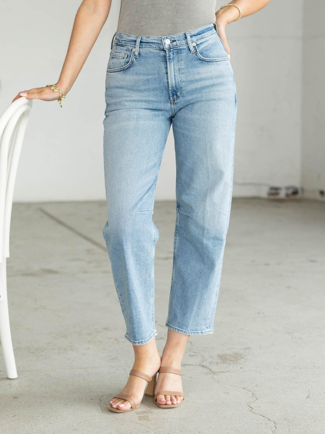Person wearing light blue jeans standing in a minimalistic room.