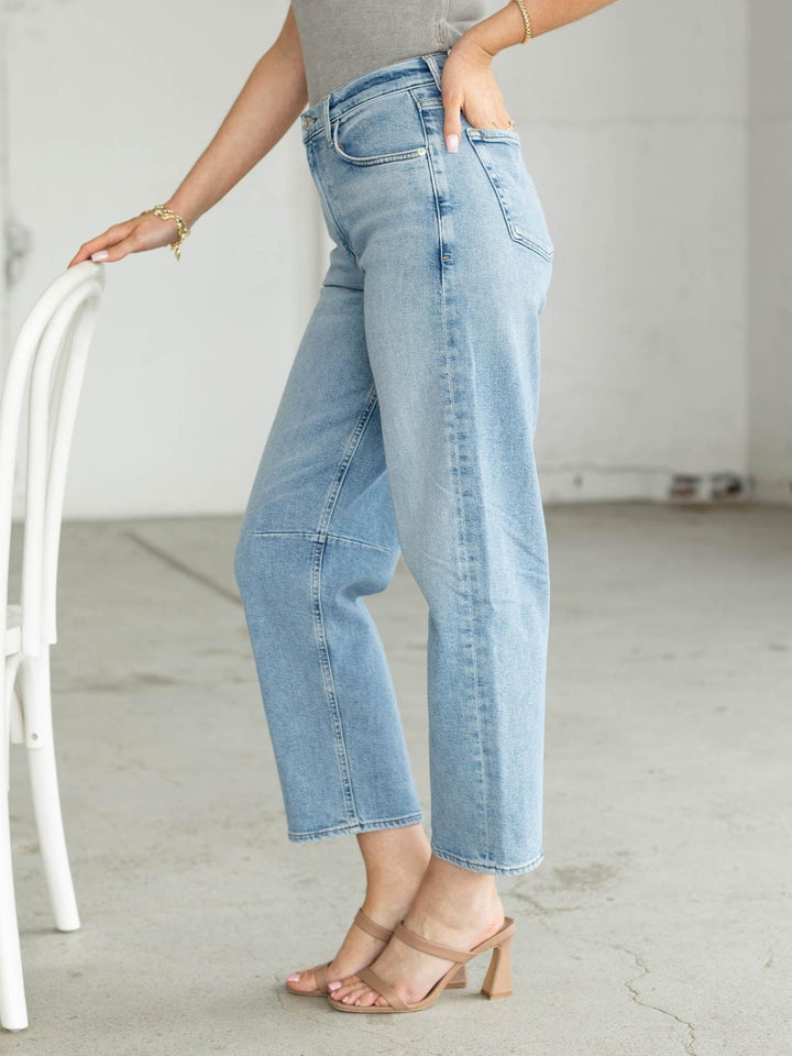 Person wearing light blue jeans standing in a minimalistic room.