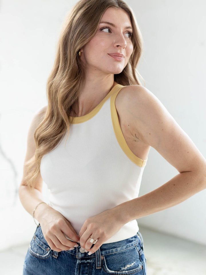 White ribbed cotton tank top with yellow color-contrasted trim, worn by a woman with long blonde hair.