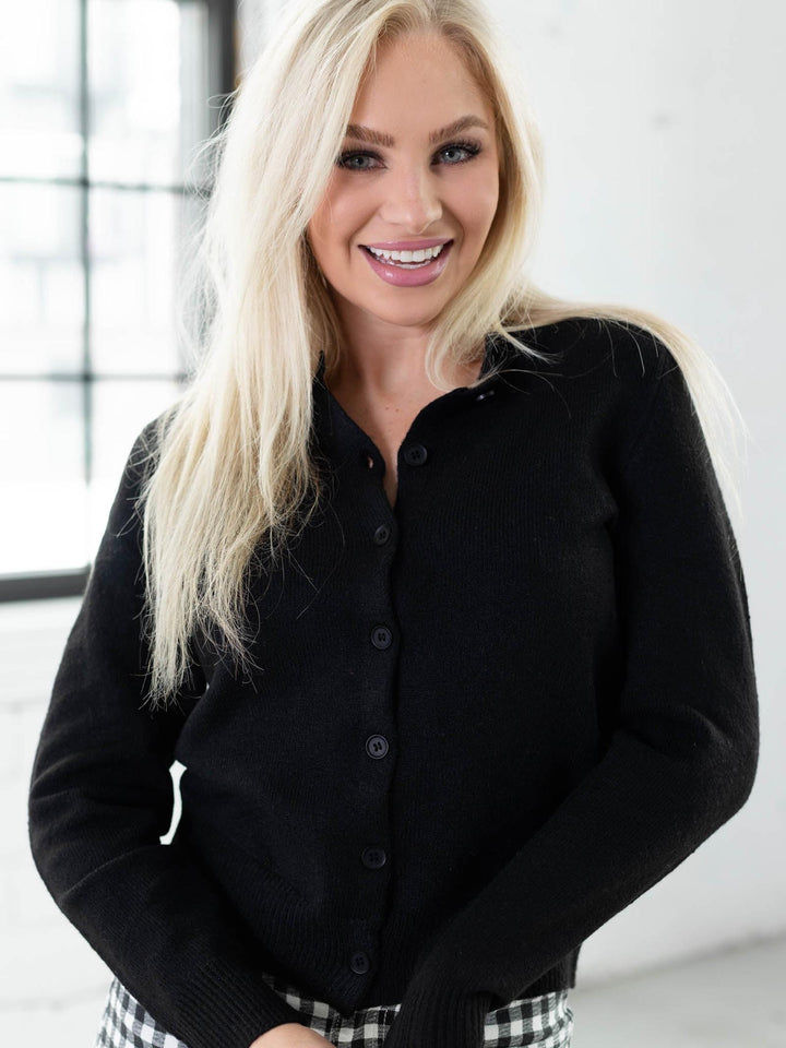 Woman wearing a black cardigan in an indoor setting