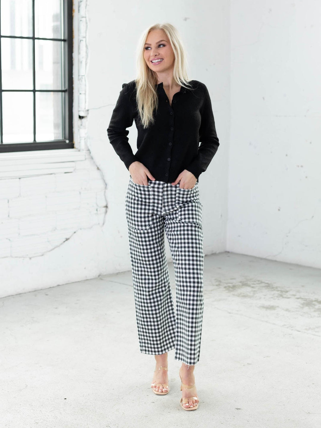 Woman wearing a black shirt and gingham pants in a white room.