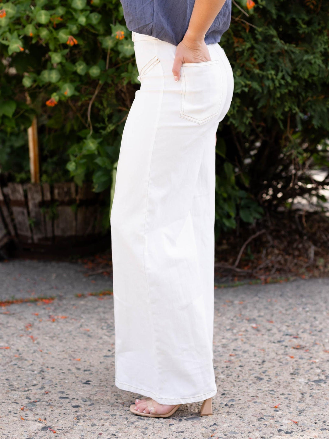 Cream high waist flare pant with contrast top stitching, flap-over button waistband, and side pocket detail.