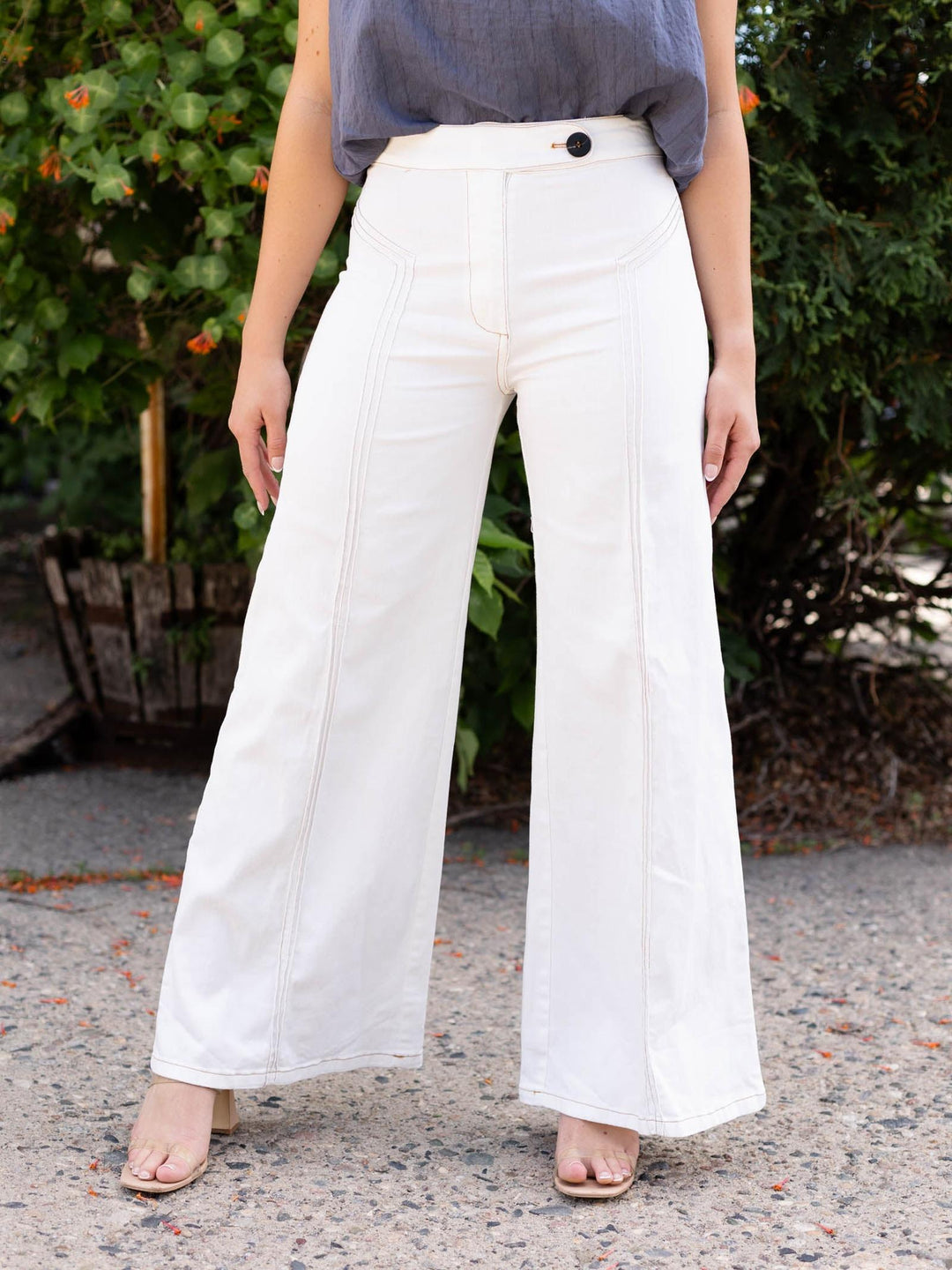 Cream high-waist flare pants with contrast top stitching and a flap-over button waistband.