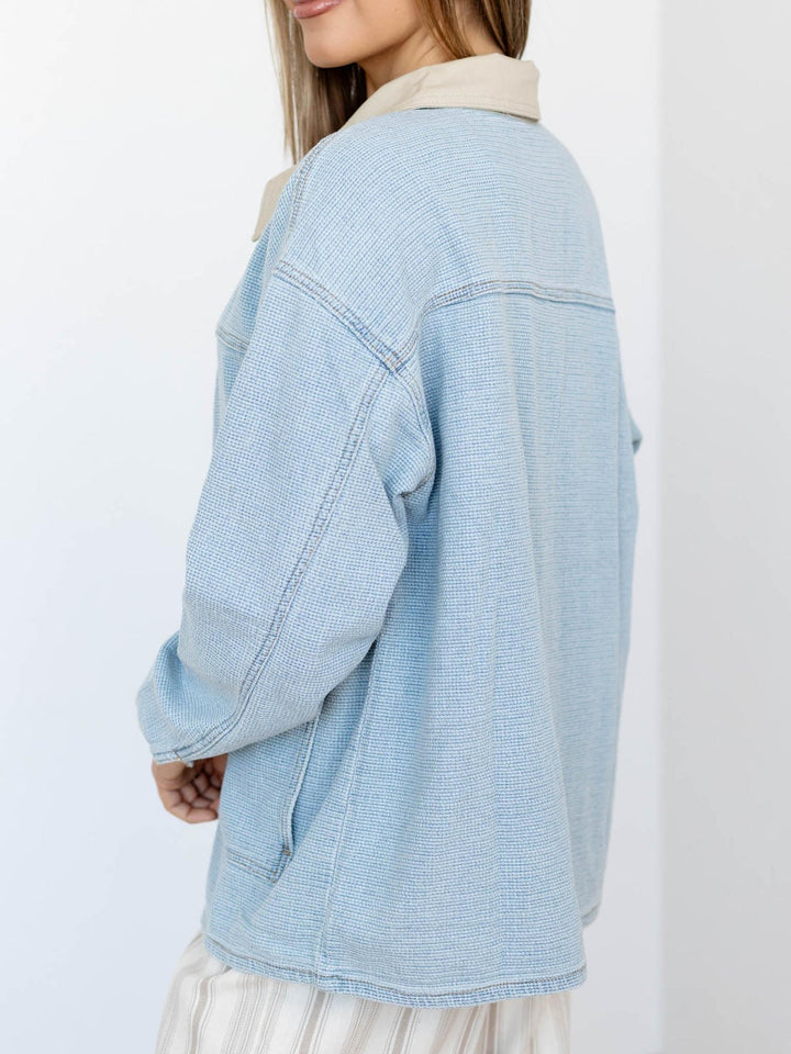 Light blue denim jacket worn by a person on a white background