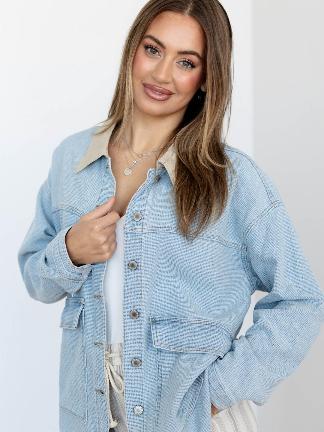 Woman wearing a light blue denim jacket against a white background