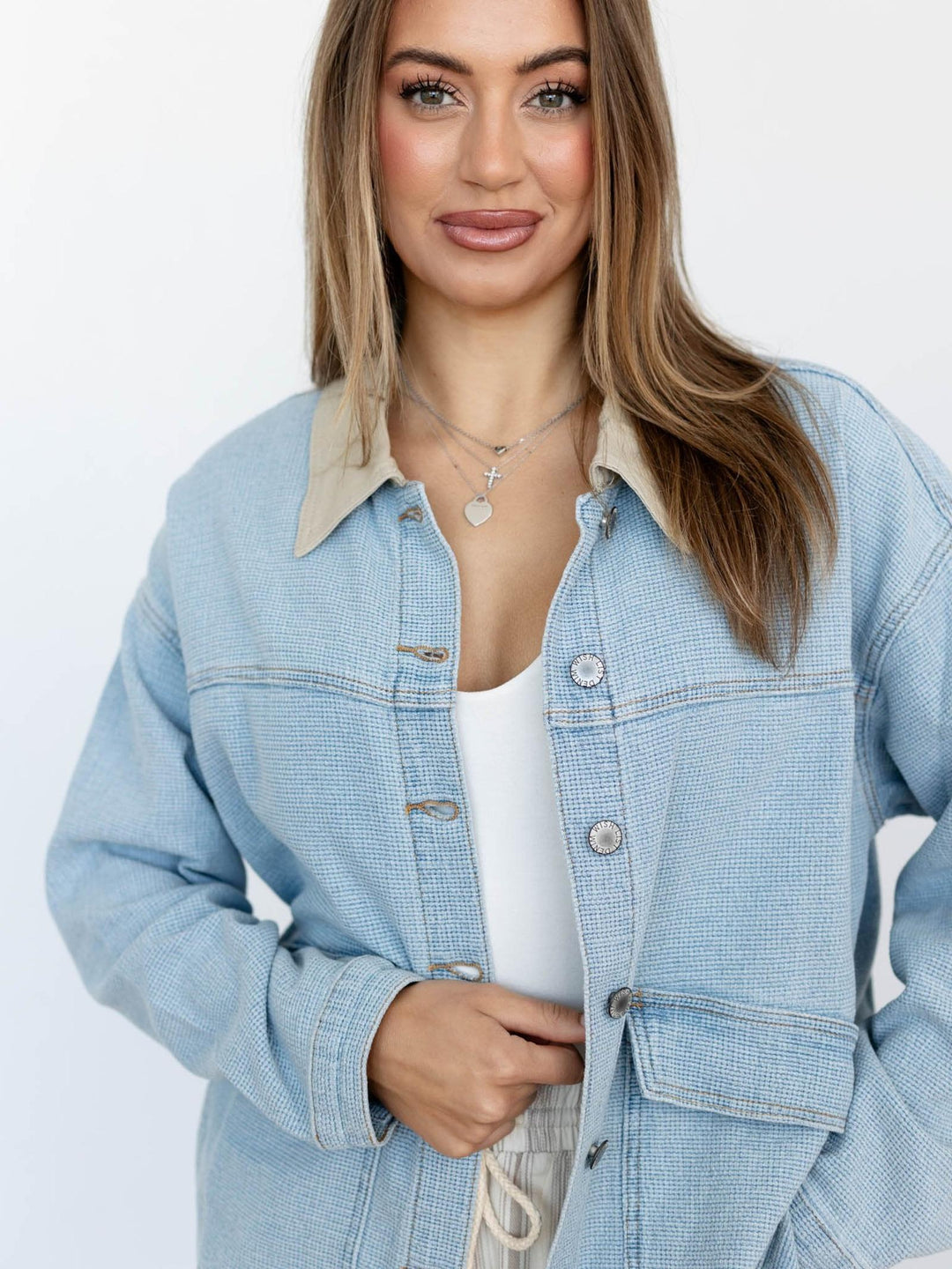 Woman wearing a light blue denim jacket on a white background