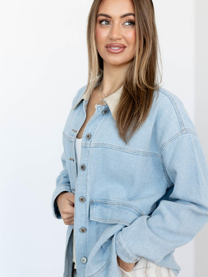 Woman wearing a light blue denim jacket on a white background