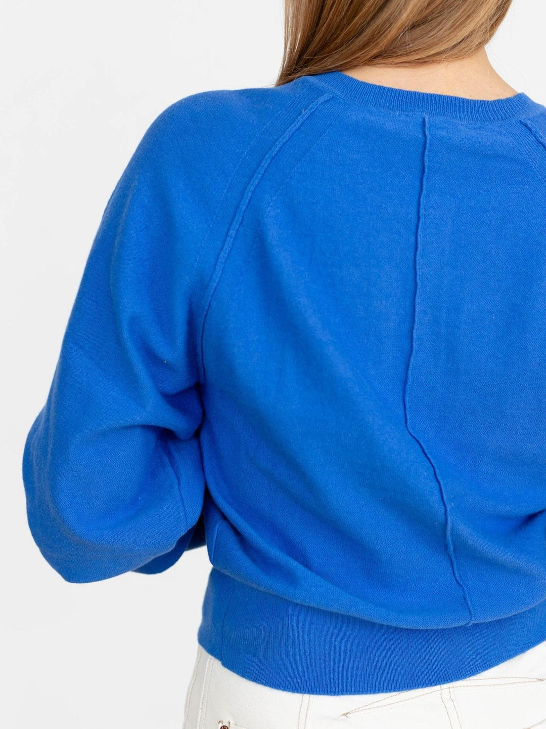Blue sweater worn by a person on a white background