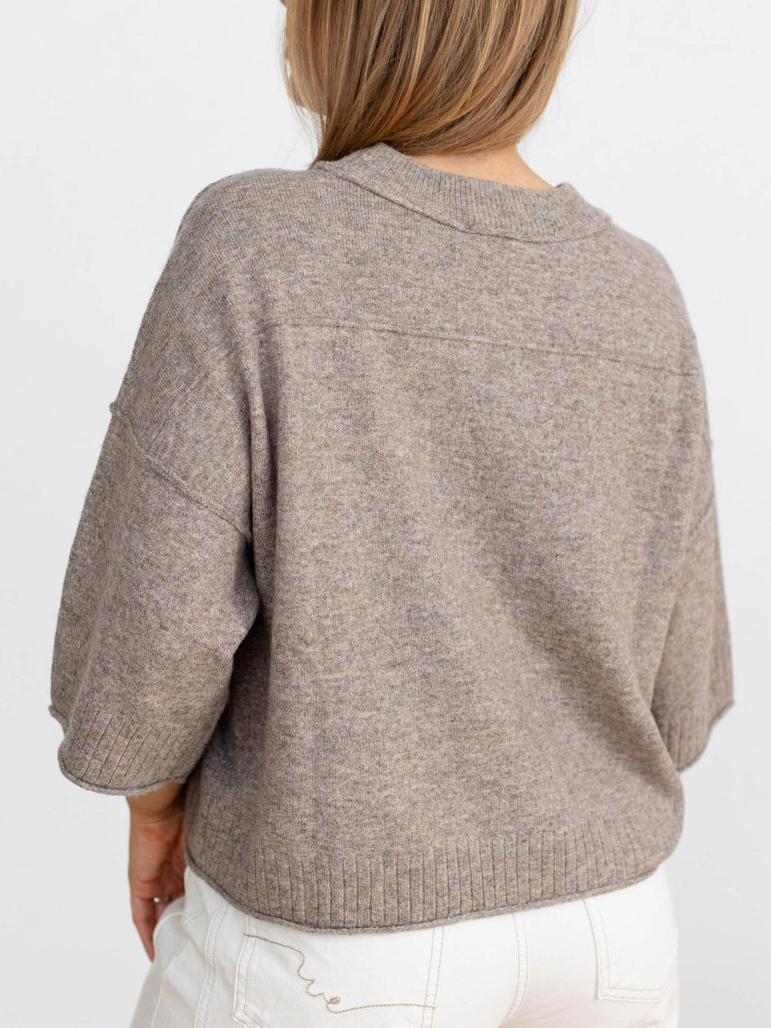 Person wearing a brown sweater on a white background