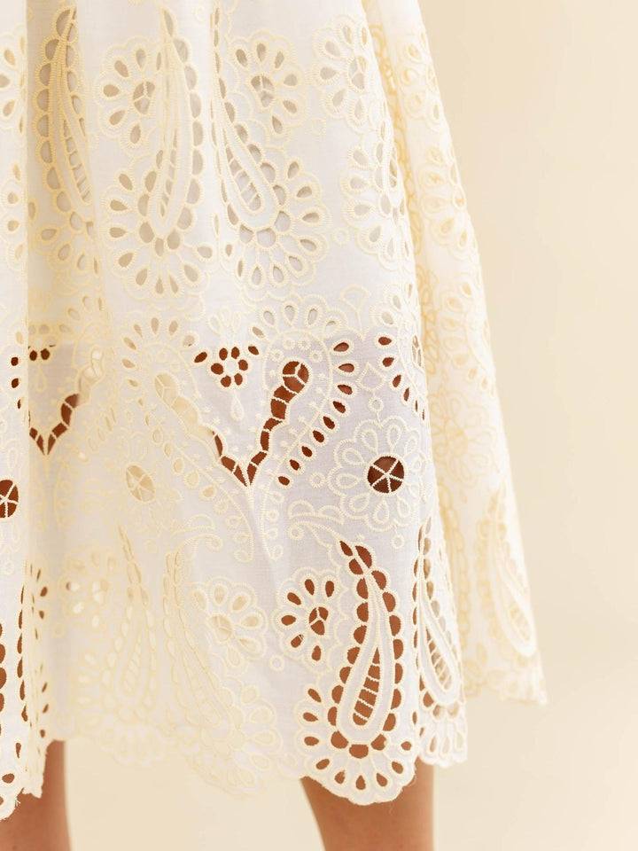 Close-up of a white lace garment with intricate patterns on a beige background