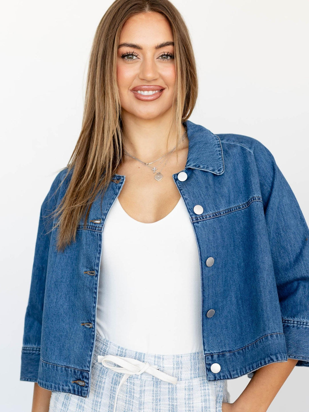 Woman wearing a blue denim jacket over a white top with a light background