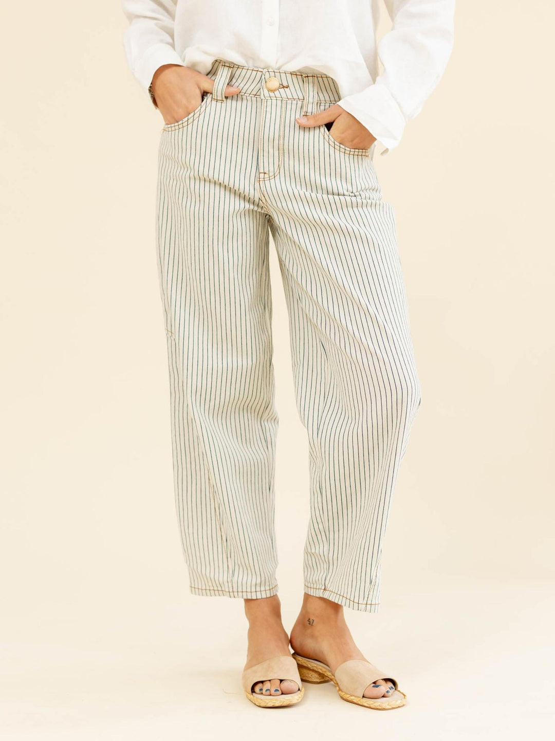 Person wearing light-colored striped pants on a beige background