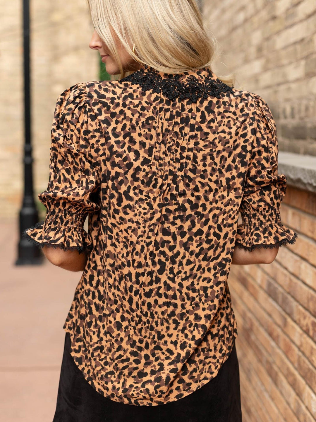 Leopard print Democracy top with black crochet lace neckline, smocked lantern sleeves, and pleated details.