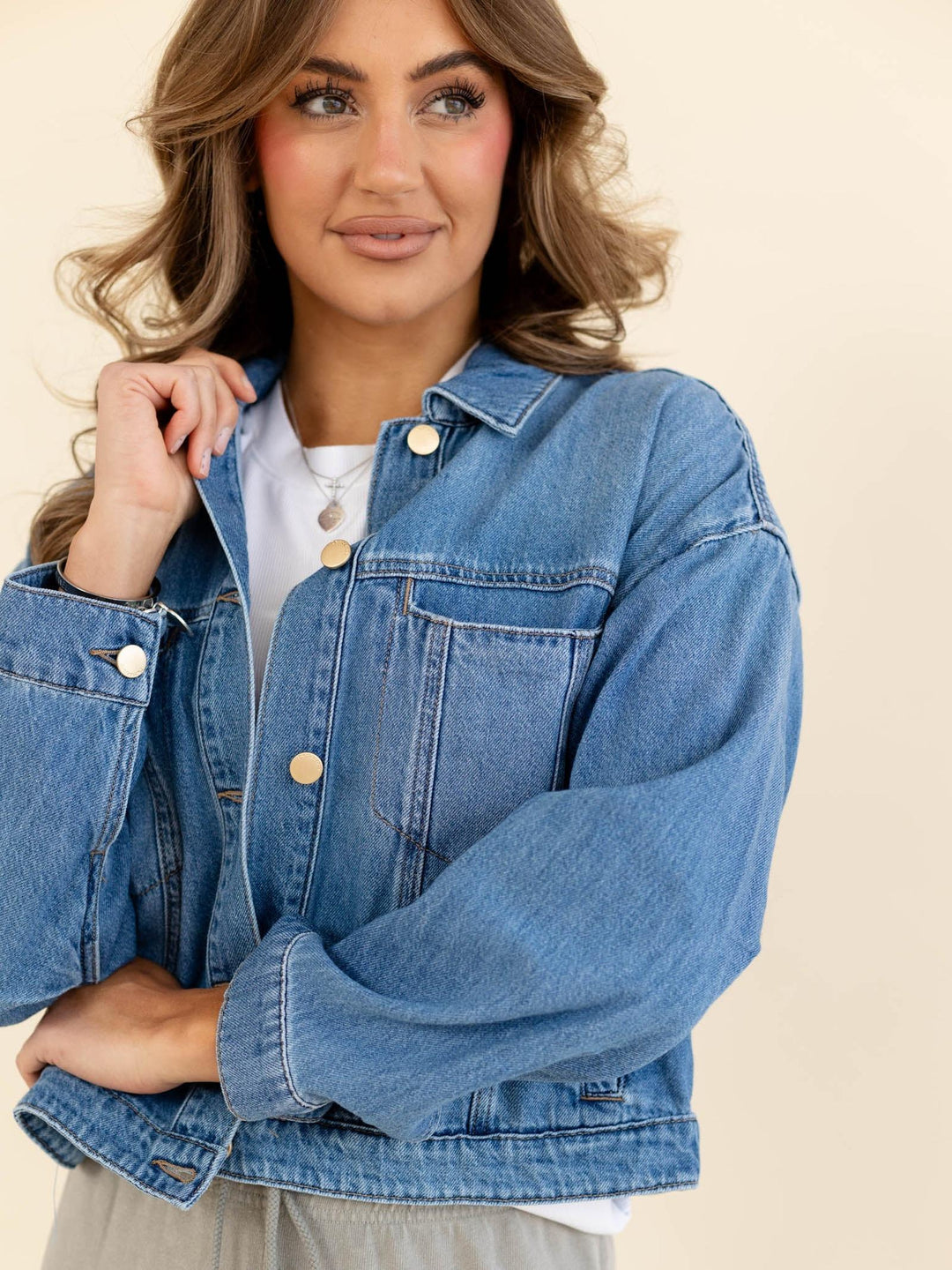 Woman wearing a blue denim jacket on a beige background
