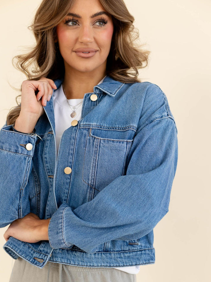 Woman wearing a blue denim jacket on a beige background