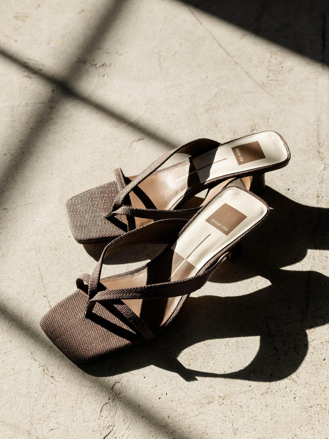 Pair of strappy high-heeled shoes on a textured surface