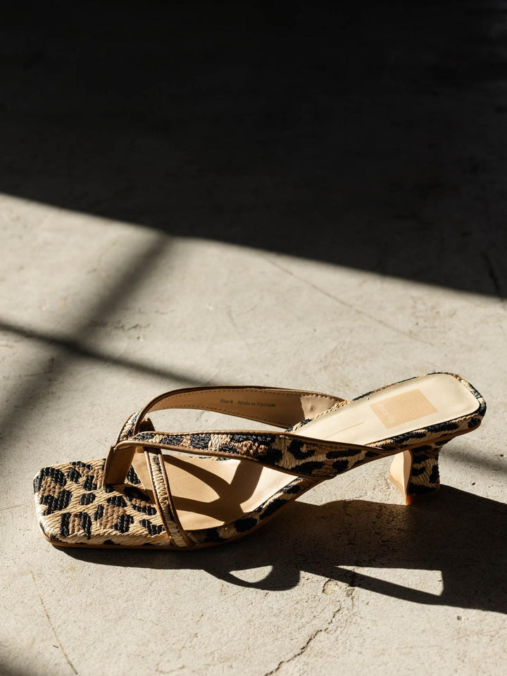 Leopard print sandal on a textured surface with sunlight casting shadows