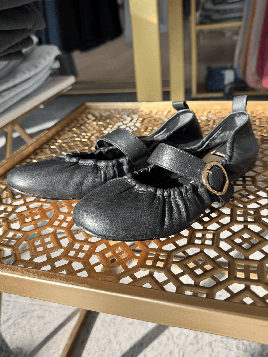 Black shoes with a gold buckle on a decorative wooden table