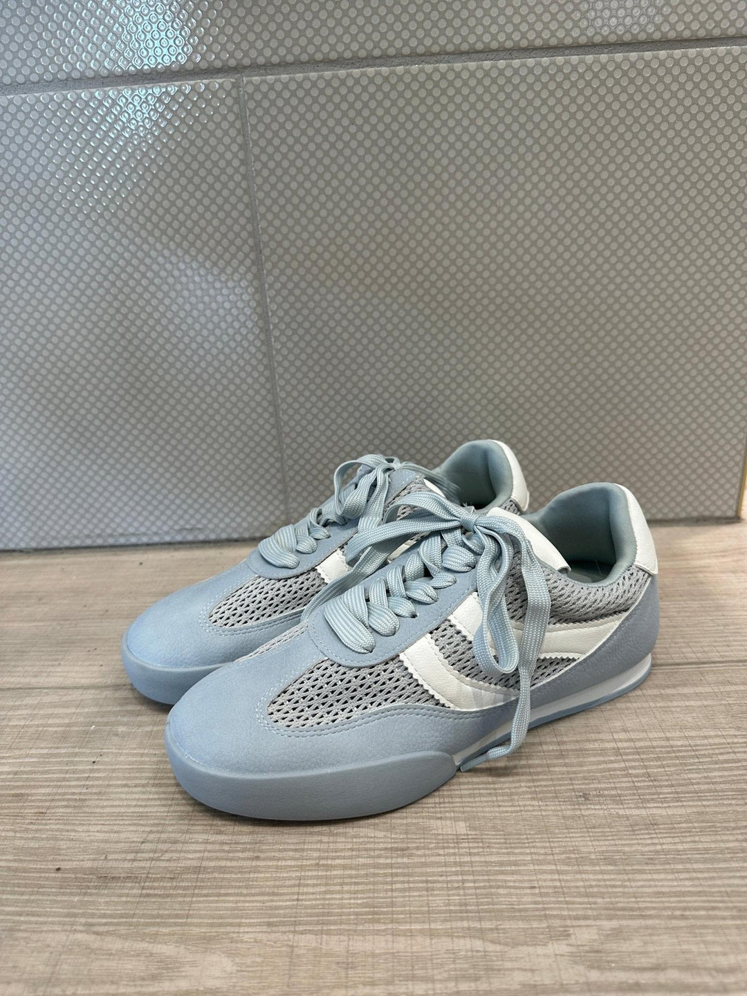 Pair of light blue sneakers on a wooden floor.